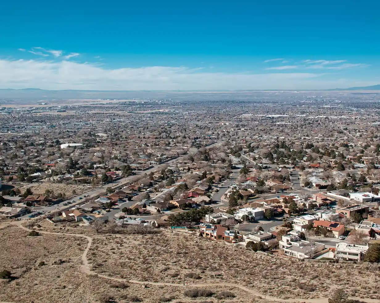 Aerial view of Albuquerque, New Mexico with the Sandia Mountains and desert under blue sky, a charter bus route