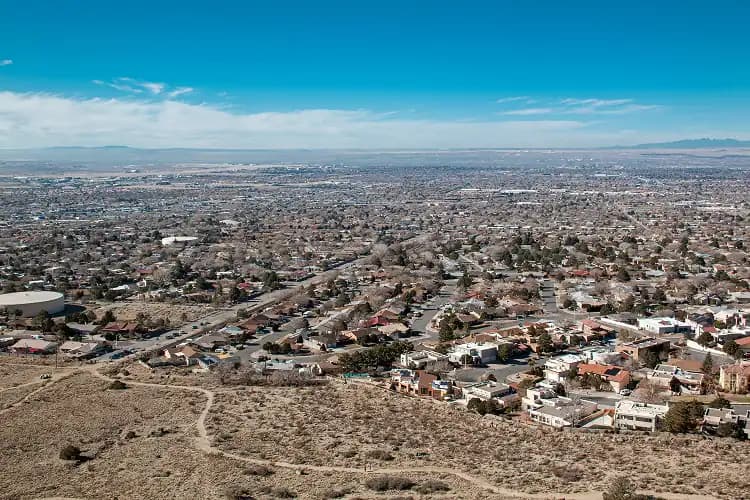 Aerial view of Albuquerque, New Mexico with the Sandia Mountains and desert under blue sky, a charter bus route