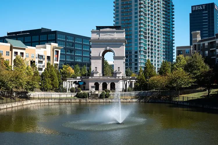 Millennium Gate triumphal arch and reflecting pond in Atlanta, Georgia with the skyline behind it, near Atlantic Station charter bus pickups