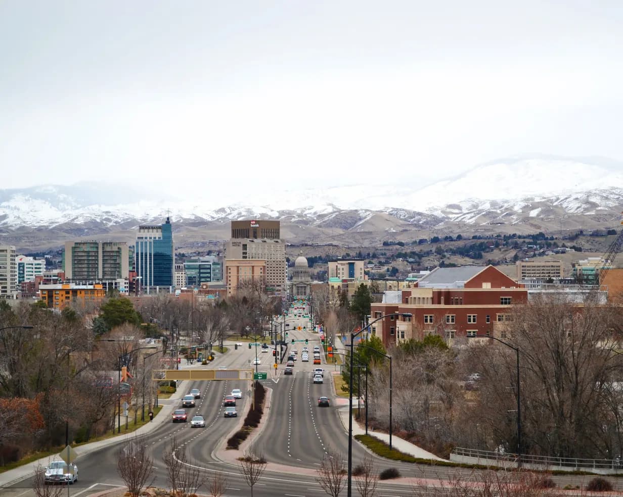 Capitol Boulevard leading to the Idaho State Capitol in downtown Boise, Idaho, with snow-covered foothills behind