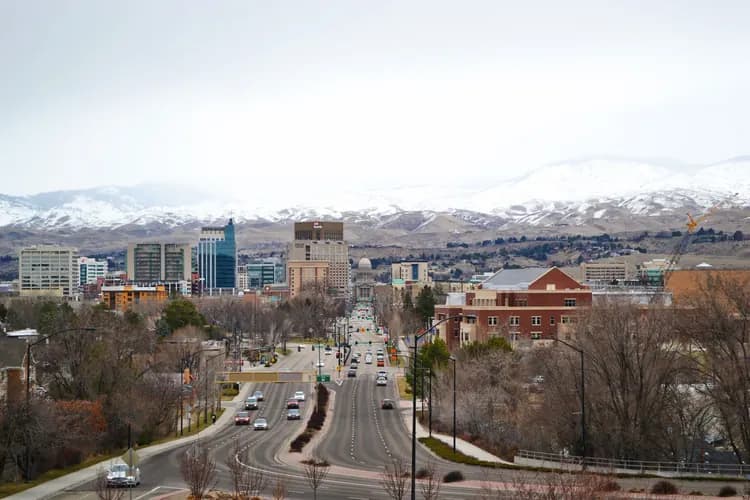 Capitol Boulevard leading to the Idaho State Capitol in downtown Boise, Idaho, with snow-covered foothills behind