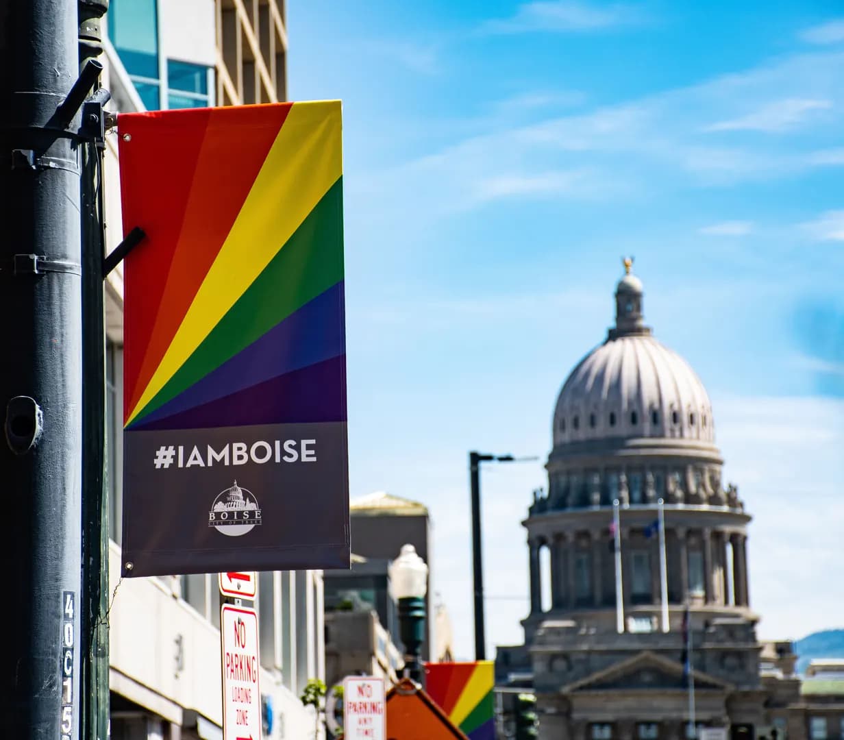Rainbow #IAMBOISE banner on a downtown light pole, with the Idaho State Capitol dome behind, in Boise, Idaho