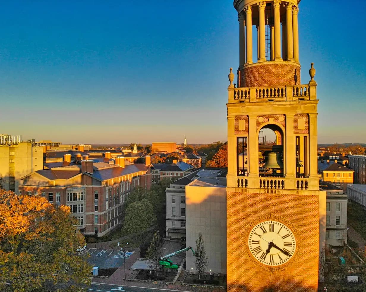 Morehead-Patterson Bell Tower at UNC Chapel Hill in golden light, above brick campus buildings in Chapel Hill, North Carolina