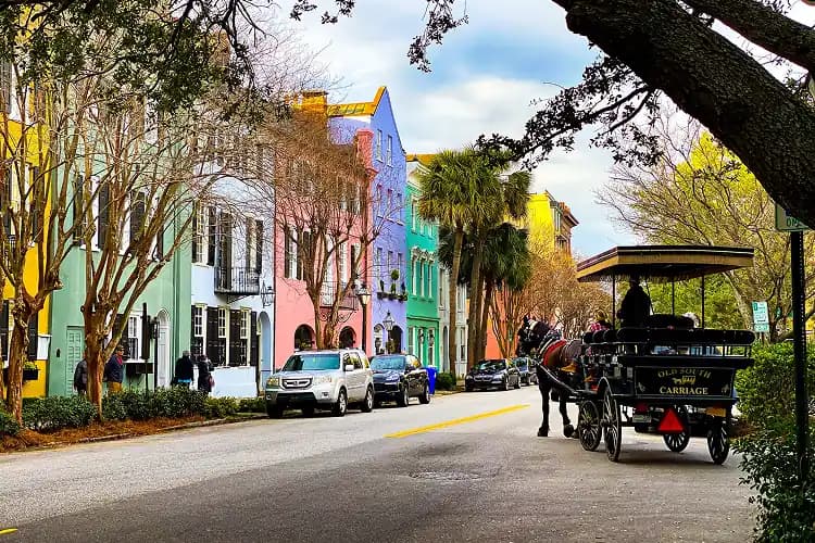 Horse-drawn carriage passing the colorful houses of Rainbow Row in downtown Charleston, South Carolina, where charter bus groups are dropped for walking tours