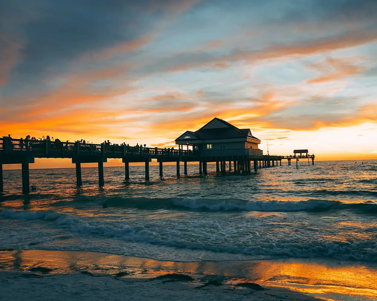 Pier silhouetted against a golden sunset over the water at Clearwater Beach, Florida, where charter bus wedding shuttles run