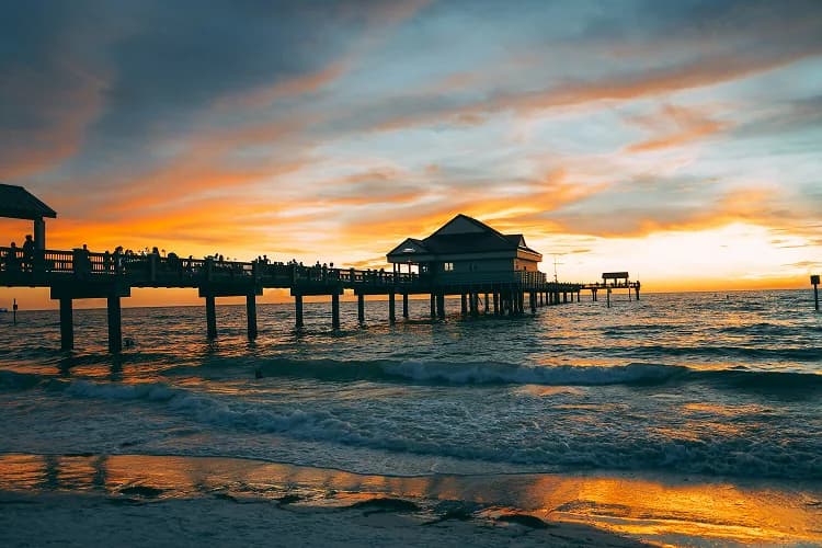 Pier silhouetted against a golden sunset over the water at Clearwater Beach, Florida, where charter bus wedding shuttles run
