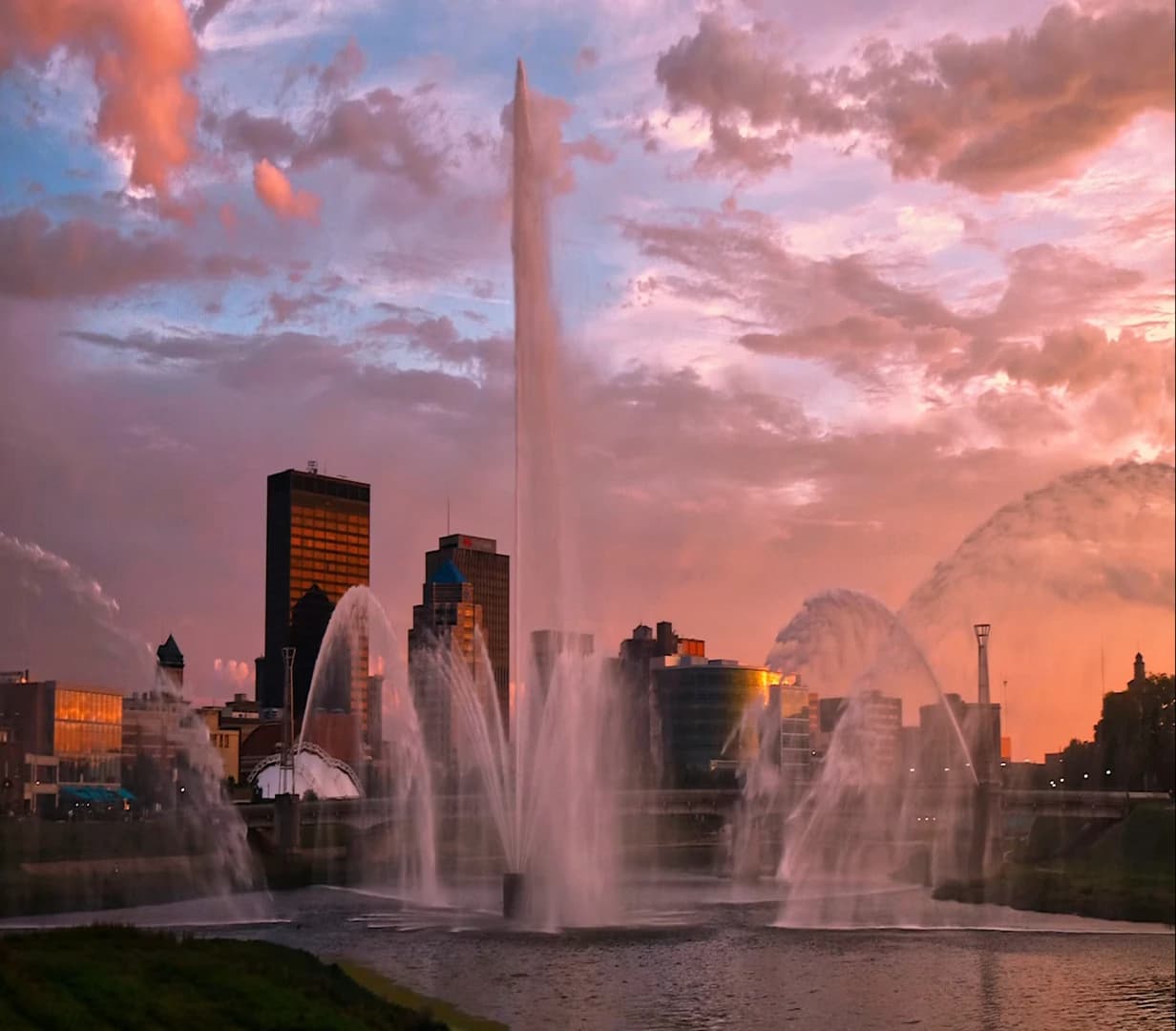 RiverScape MetroPark fountain and the downtown Dayton, Ohio skyline at dusk, a riverfront stop for charter bus groups