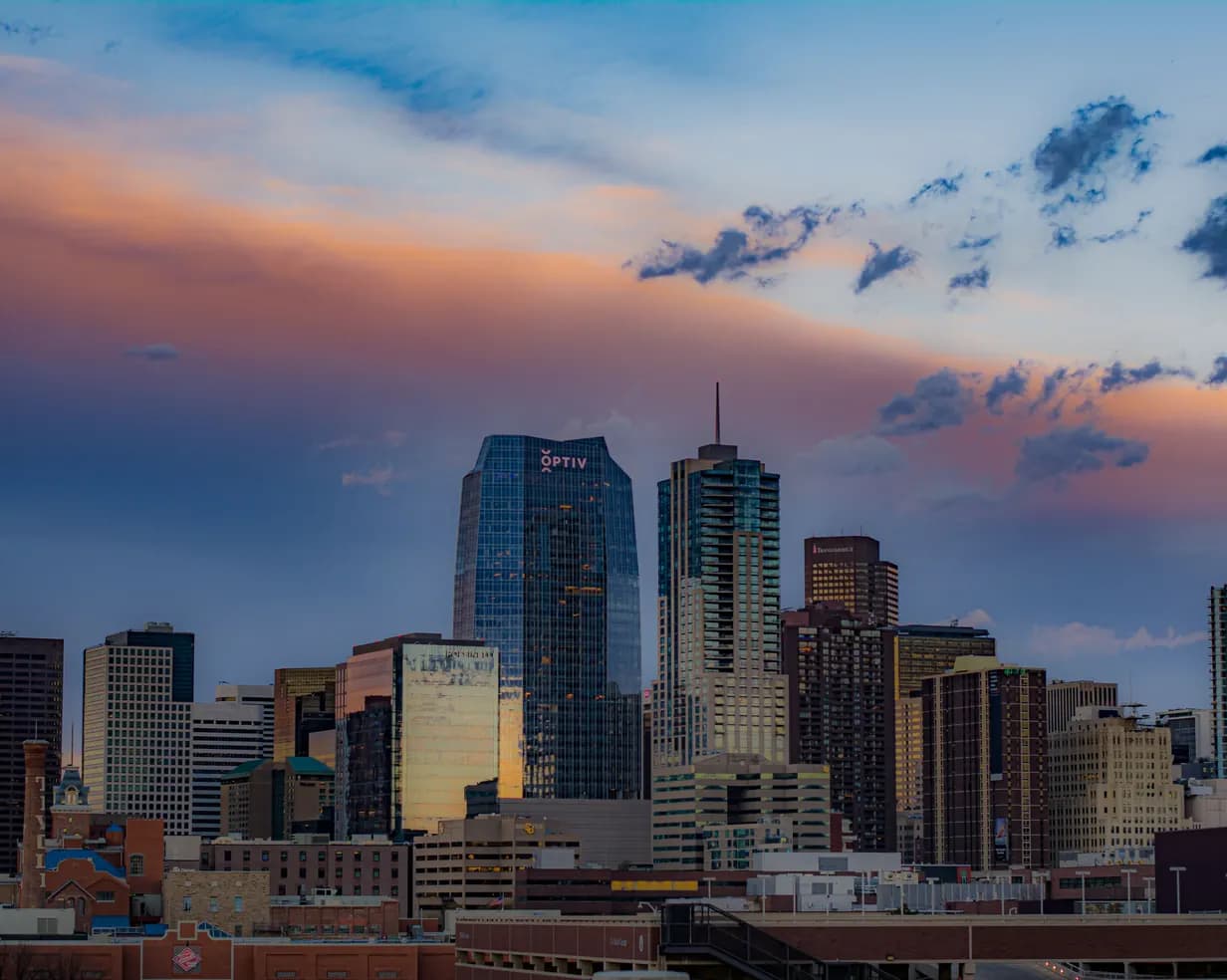 Downtown Denver, Colorado skyline at sunset, with pink and orange clouds over the high-rise towers