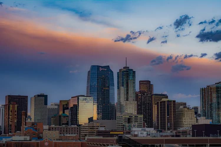 Downtown Denver, Colorado skyline at sunset, with pink and orange clouds over the high-rise towers