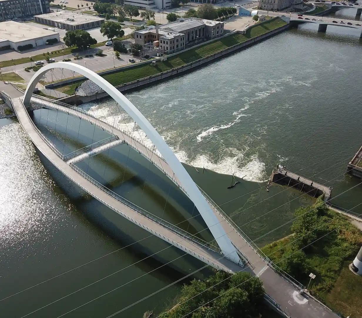 Aerial view of the Principal Riverwalk pedestrian bridge arch over the Des Moines River, a charter bus downtown route