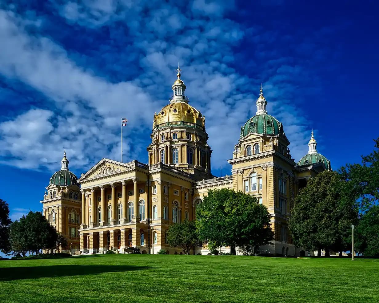 Gold dome of the Iowa State Capitol above a green lawn in Des Moines, Iowa, a charter bus lobby-day stop