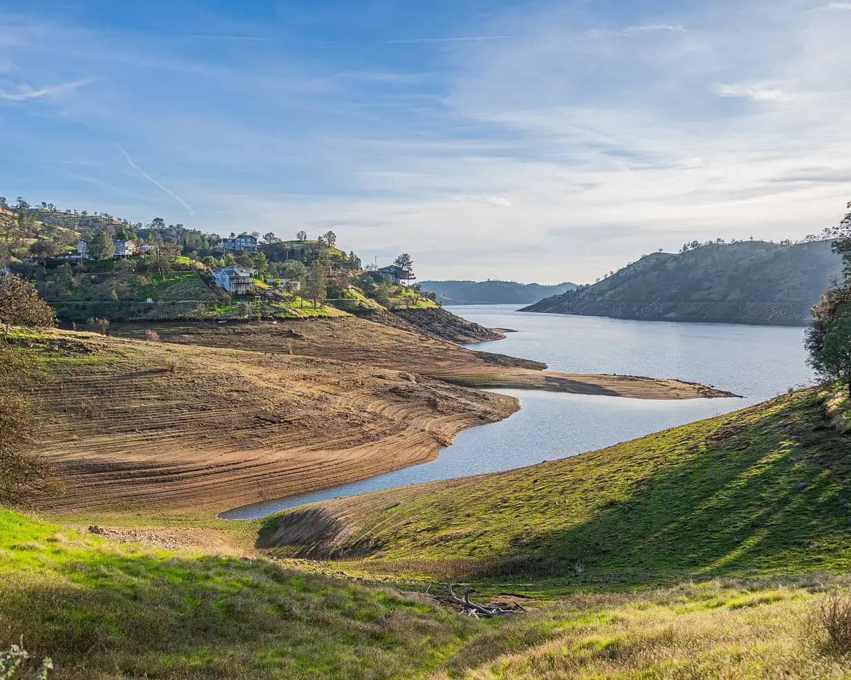 Winding reservoir between green foothills, with homes on the slopes, at Millerton Lake near Fresno, California