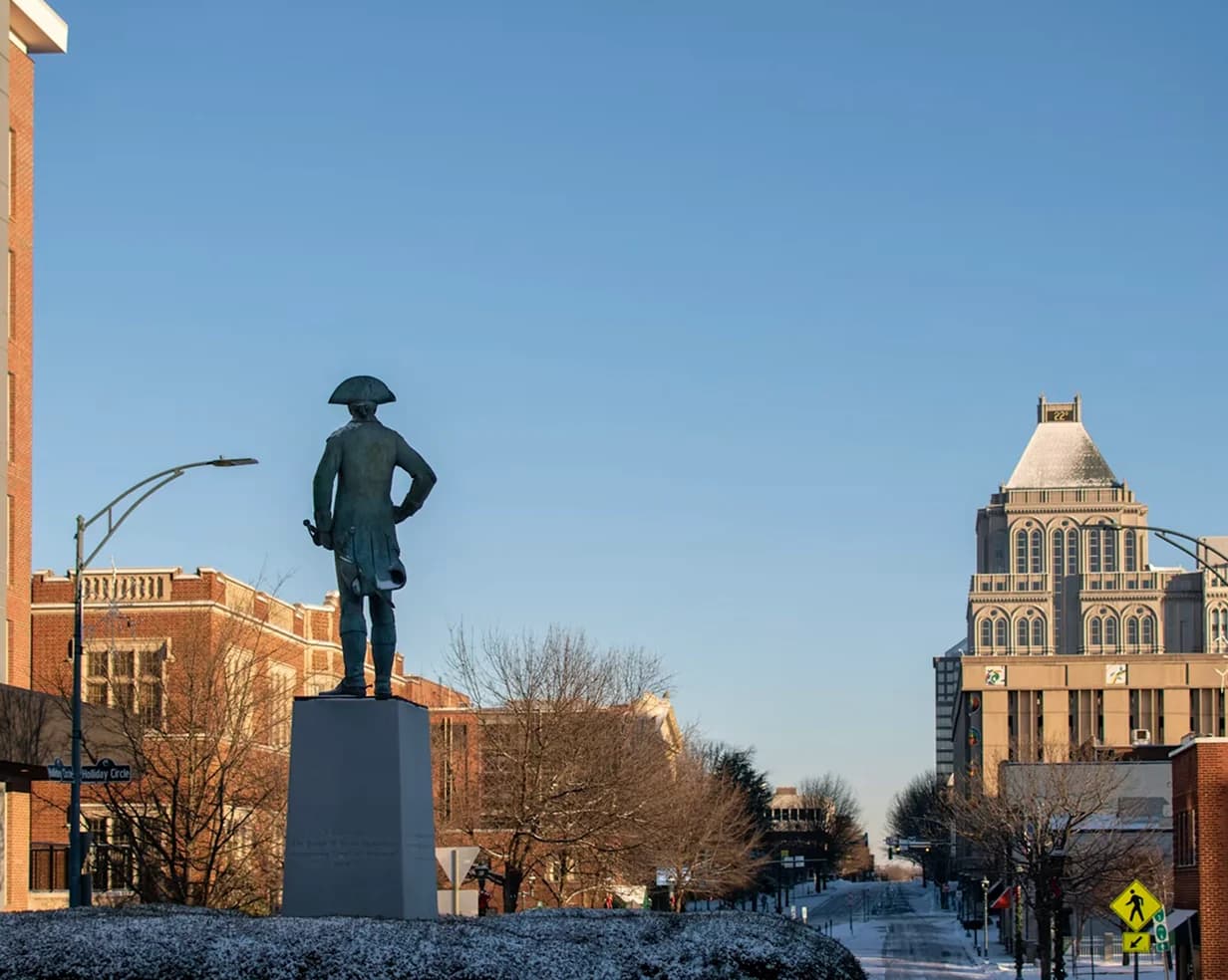 Revolutionary War statue in downtown Greensboro, North Carolina in winter, near the Art Deco buildings where charter bus groups stage hotel pickups