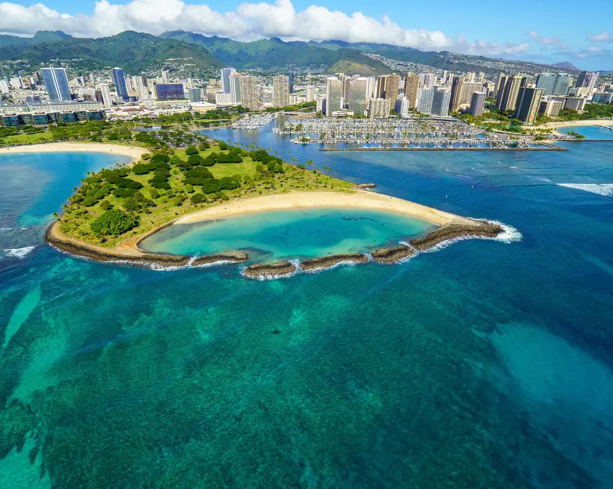 Aerial view of the Magic Island lagoon at Ala Moana Beach Park with the Waikiki skyline and mountains in Honolulu, Hawaii