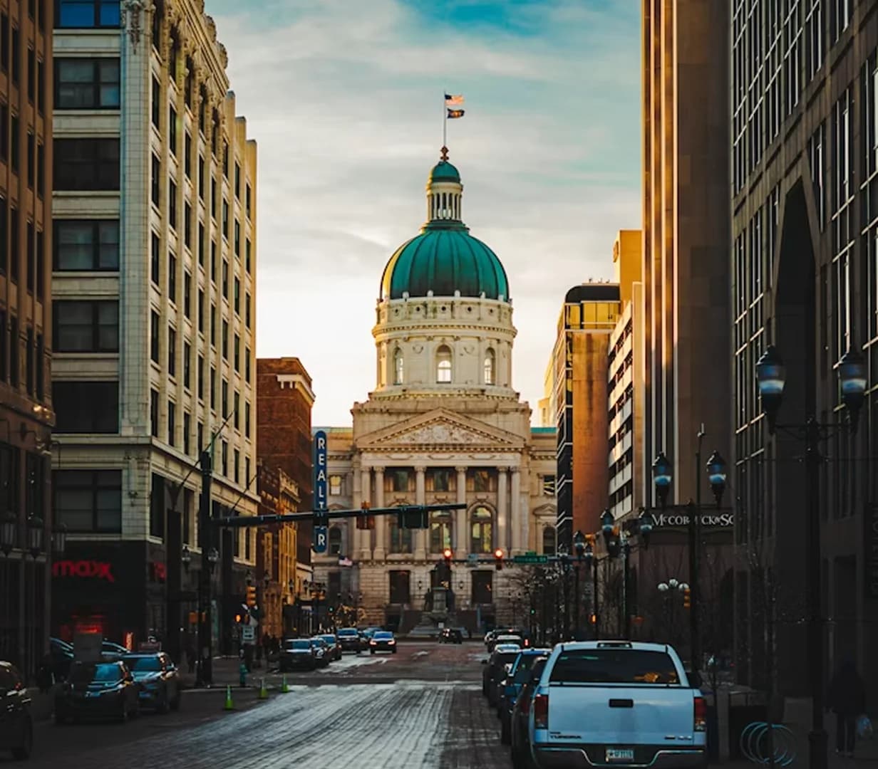 Green dome of the Indiana Statehouse above a downtown Indianapolis street, on the routes charter bus operators run daily