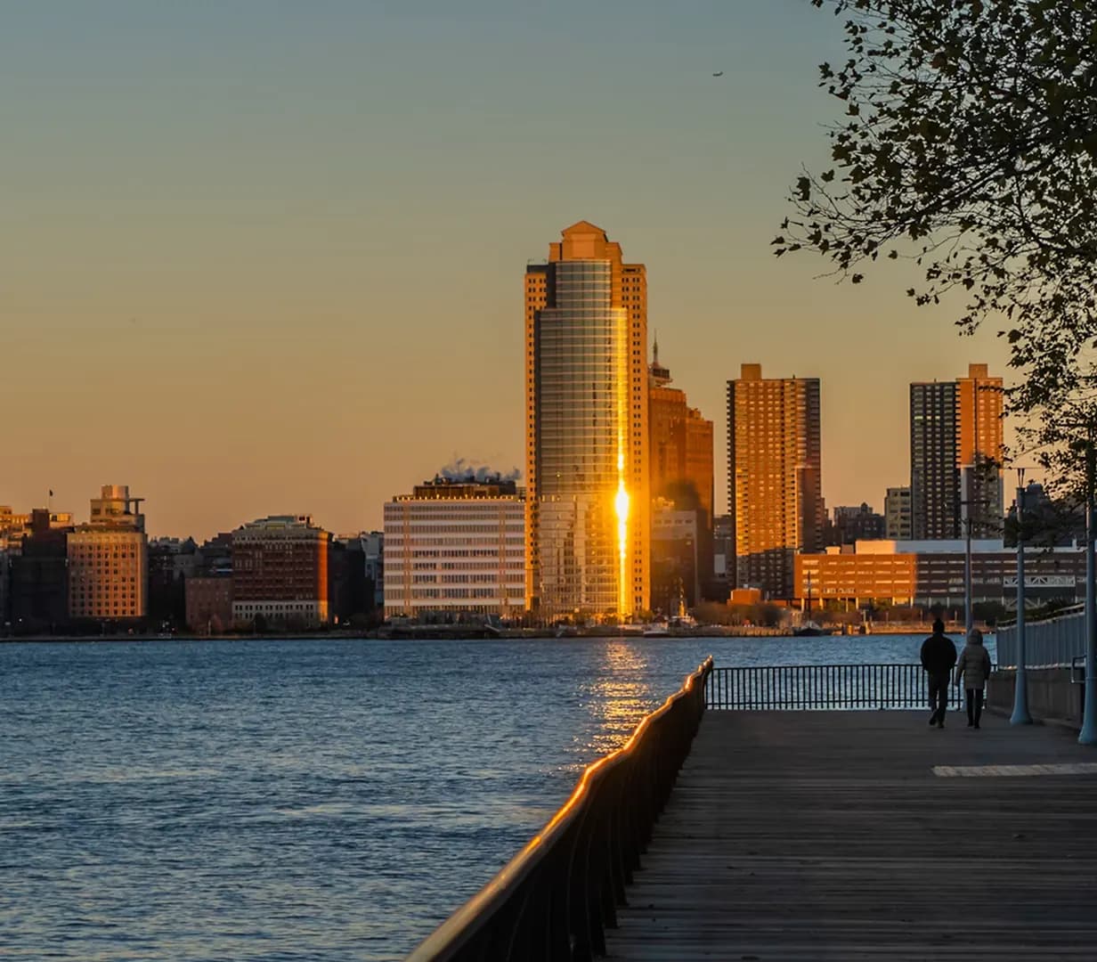 Waterfront boardwalk along the Hudson River at sunset in Jersey City, New Jersey, near the Exchange Place and Harborside charter bus pickup curbs