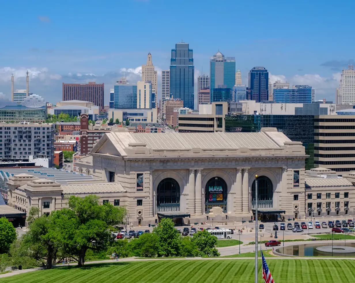 Union Station and the downtown Kansas City, Missouri skyline above a green lawn, a charter bus field-trip stop