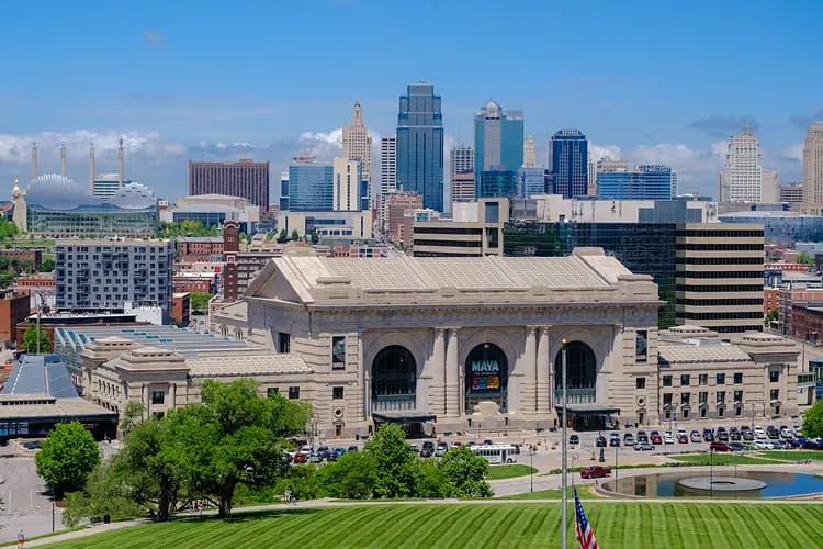 Union Station and the downtown Kansas City, Missouri skyline above a green lawn, a charter bus field-trip stop