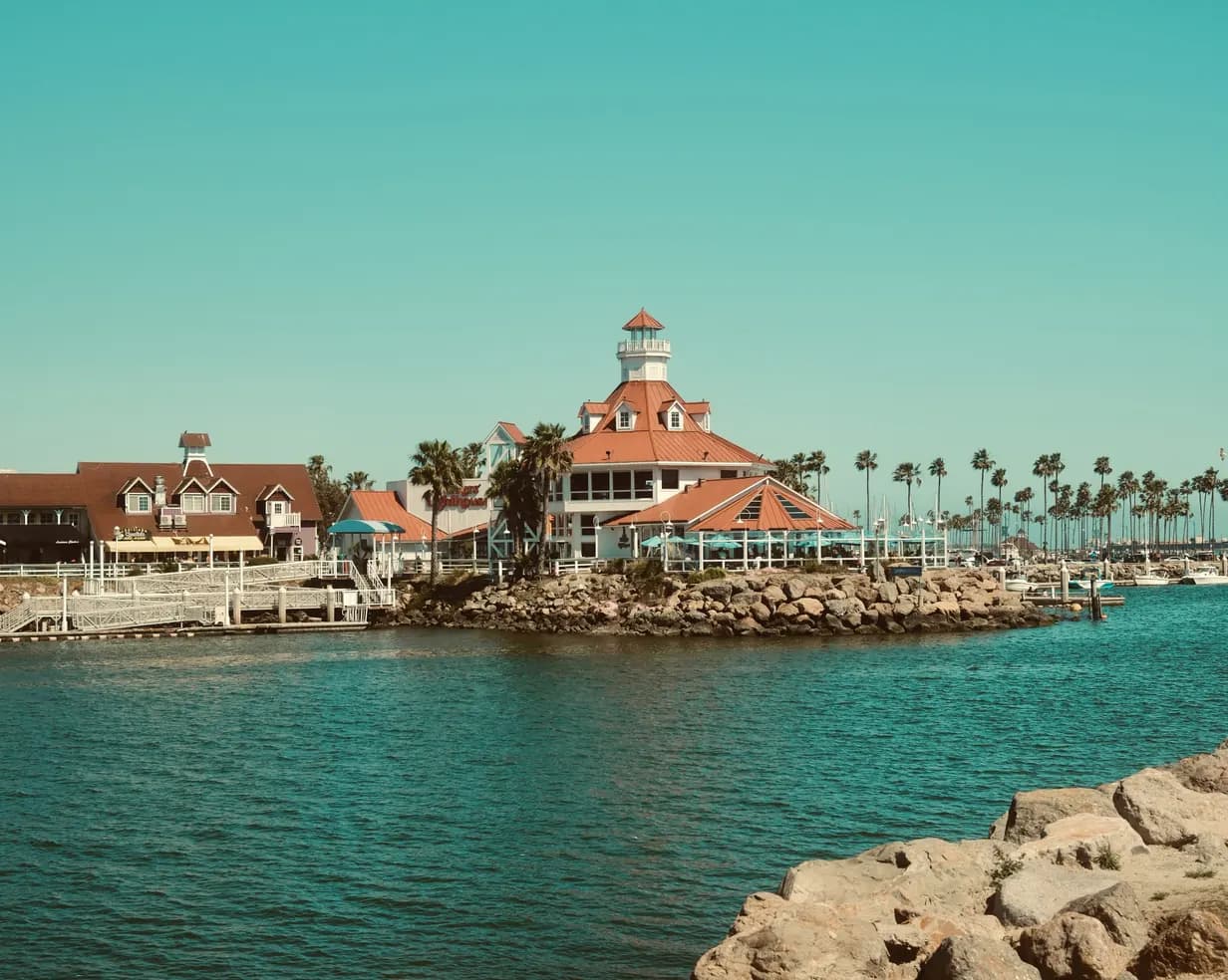 Parker's Lighthouse at Shoreline Village on the Long Beach, California waterfront, with palm trees and a rocky shore