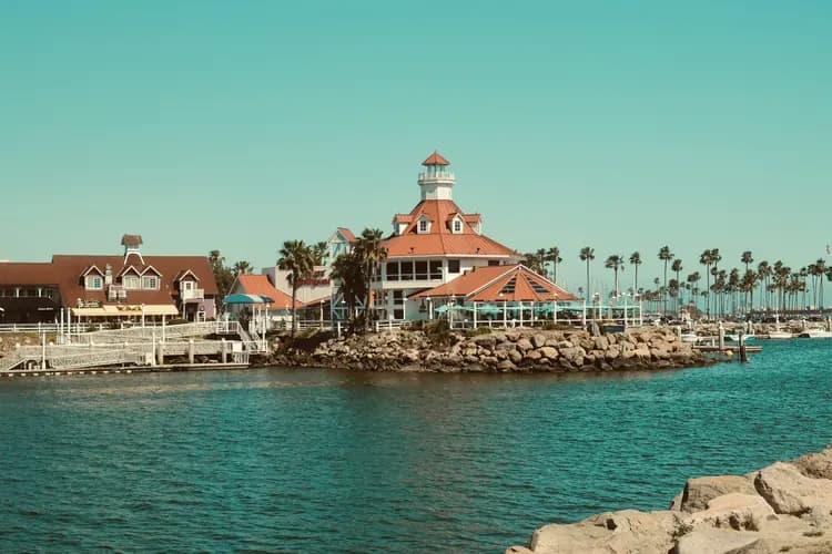 Parker's Lighthouse at Shoreline Village on the Long Beach, California waterfront, with palm trees and a rocky shore