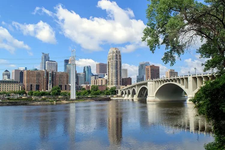 The Minneapolis skyline behind the arched Third Avenue Bridge over the Mississippi River
