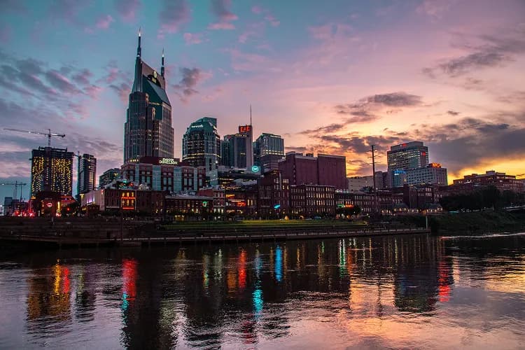 Downtown Nashville, Tennessee skyline and the AT&T Building above the Cumberland River at sunset, where charter bus groups stage for a night out