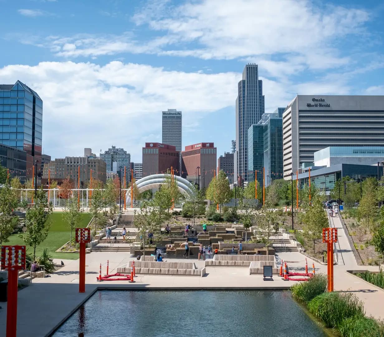Gene Leahy Mall at The RiverFront in downtown Omaha, Nebraska, with a fountain, a pond and the city skyline behind