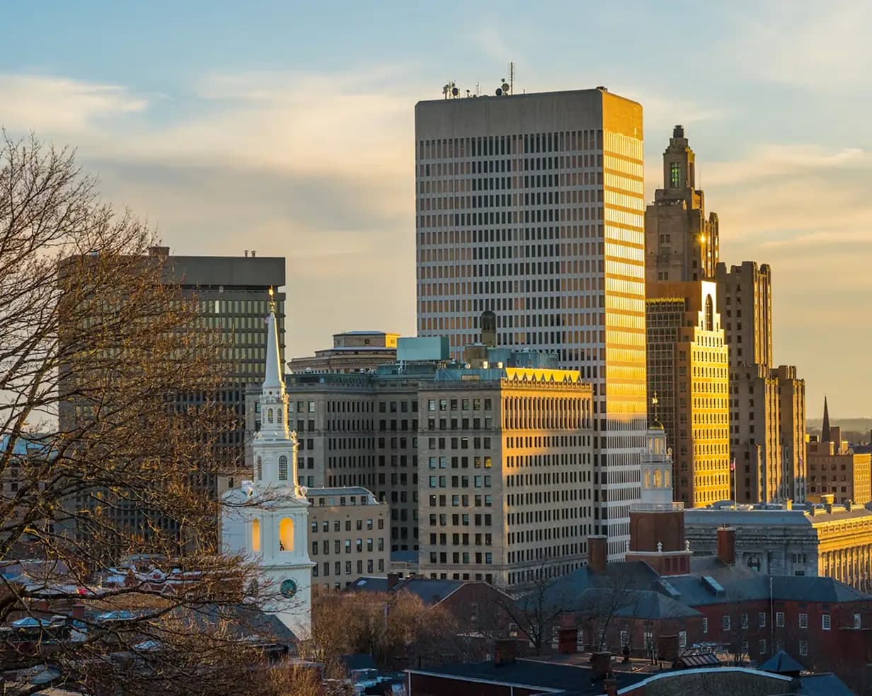 Downtown Providence, Rhode Island skyline with the First Baptist Church steeple at golden hour, where charter bus groups board for WaterFire evenings