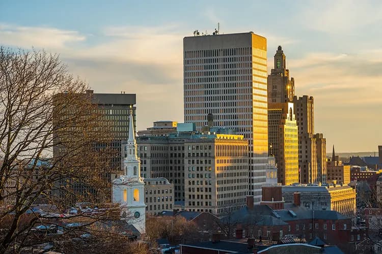 Downtown Providence, Rhode Island skyline with the First Baptist Church steeple at golden hour, where charter bus groups board for WaterFire evenings