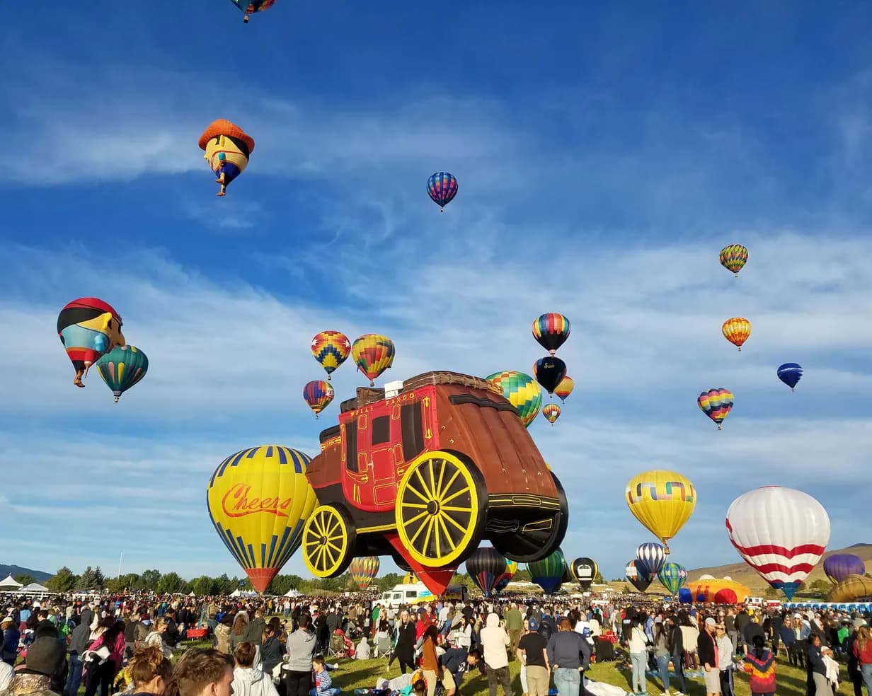 Hot air balloons, including a giant stagecoach balloon, lifting off over crowds at the Great Reno Balloon Race in Reno, Nevada
