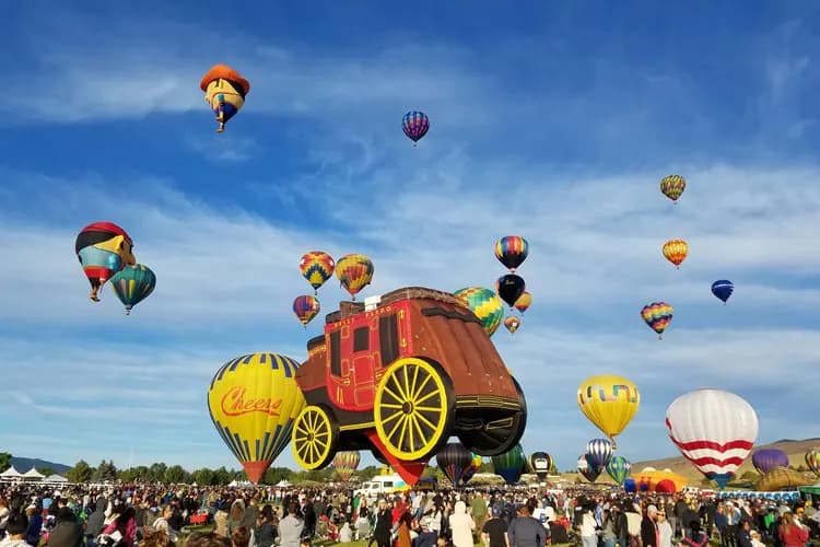 Hot air balloons, including a giant stagecoach balloon, lifting off over crowds at the Great Reno Balloon Race in Reno, Nevada
