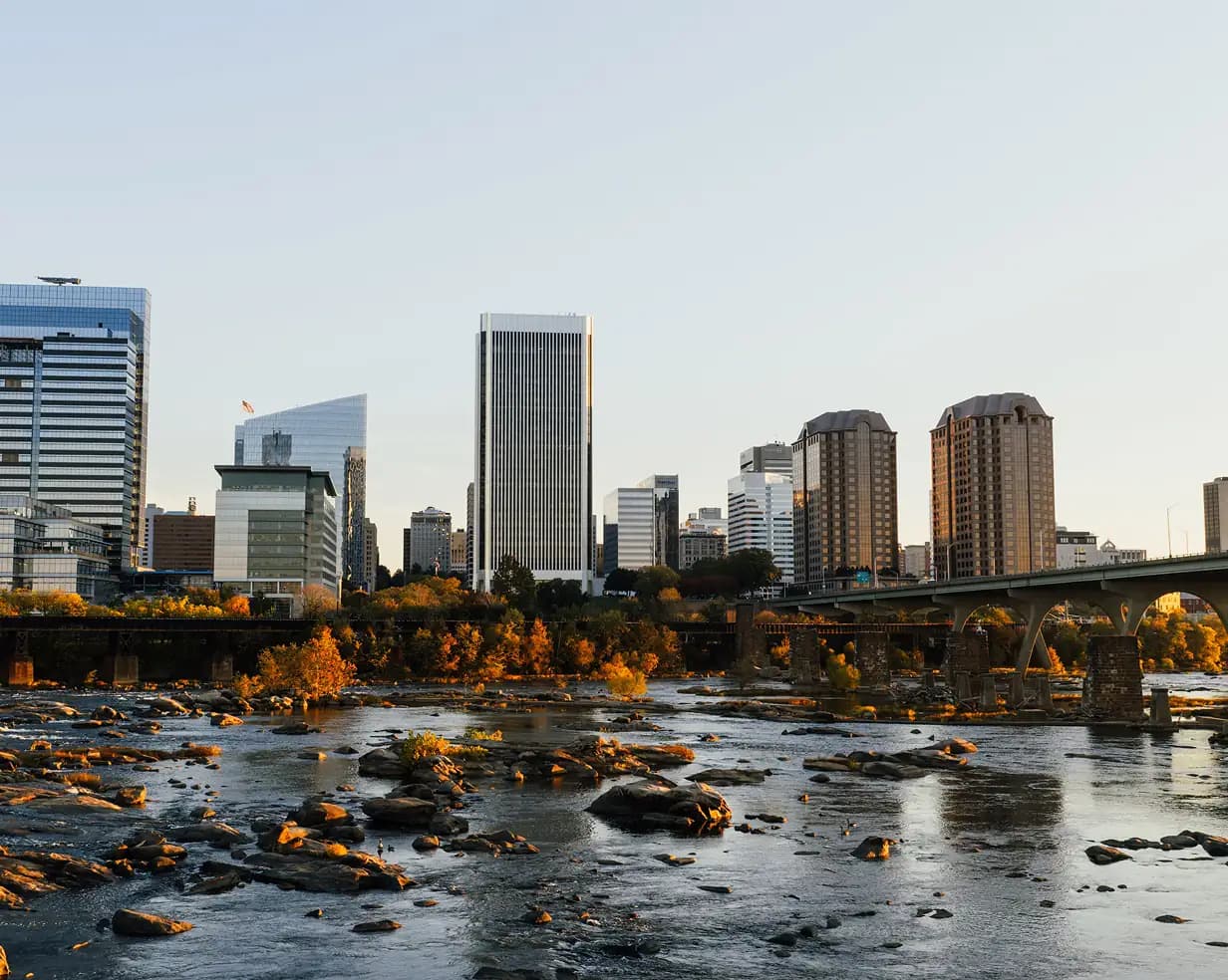 Autumn foliage along the James River with a bridge crossing and the Richmond skyline beyond