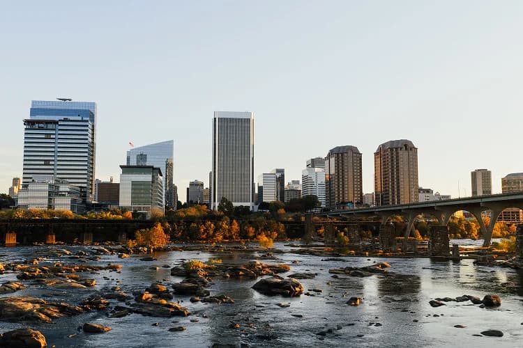 Autumn foliage along the James River with a bridge crossing and the Richmond skyline beyond