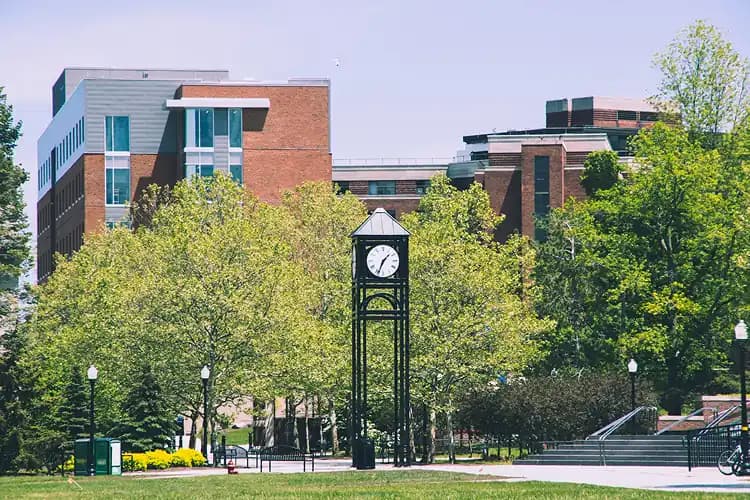 Campus clock tower framed by spring greenery in Rochester, New York, on the U of R / RIT campus visit route for charter bus groups