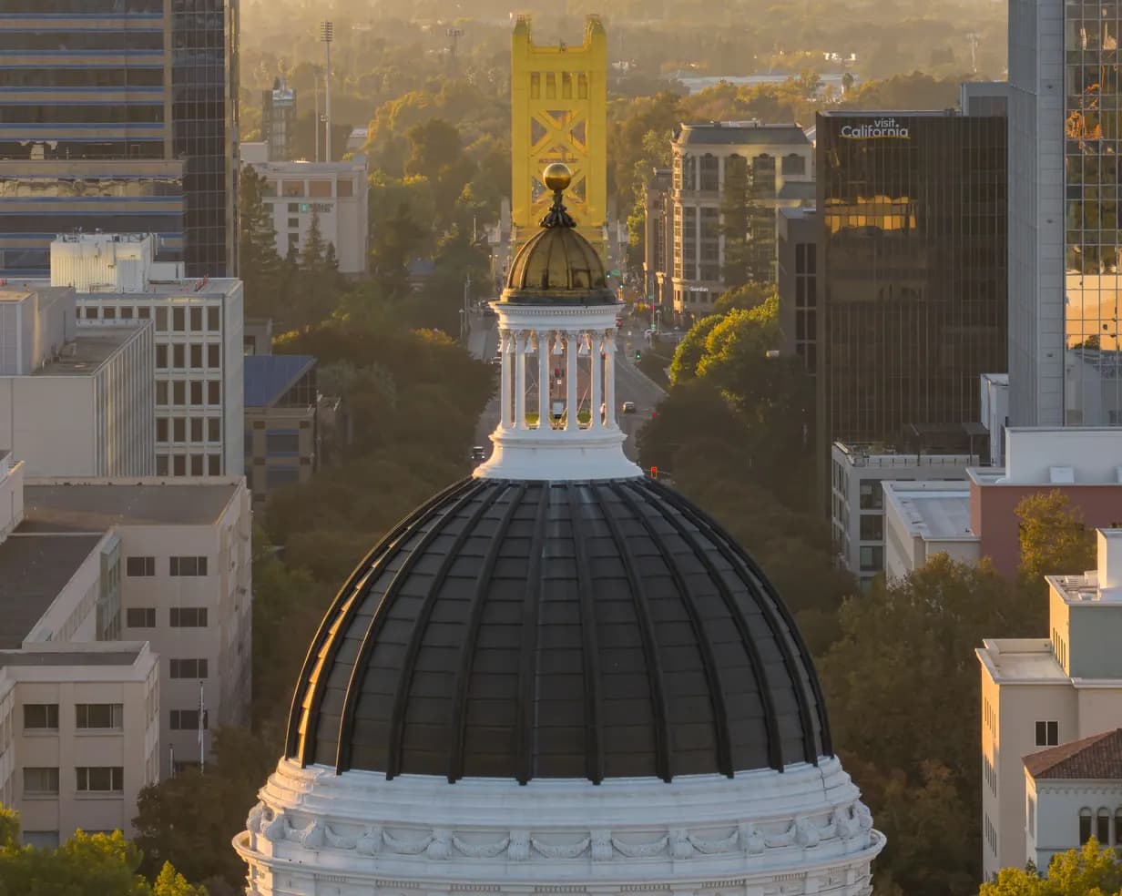California State Capitol dome with the gold Tower Bridge beyond it at sunset in downtown Sacramento, California