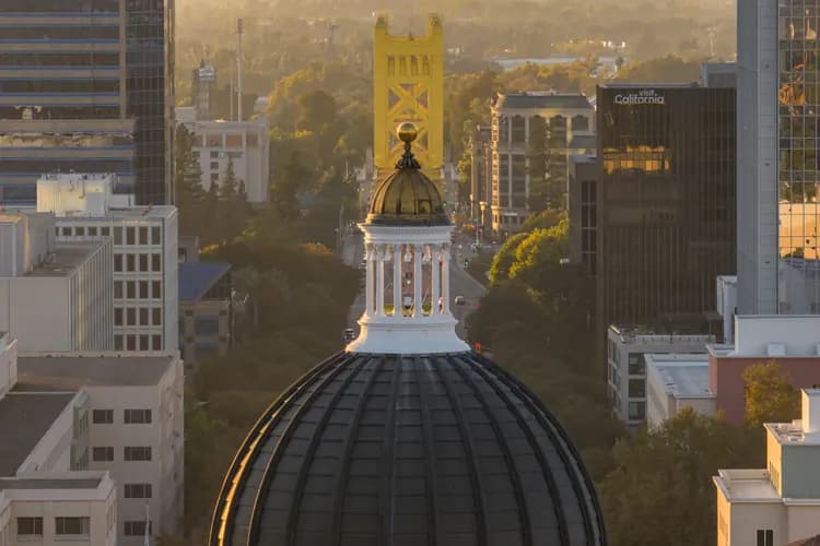 California State Capitol dome with the gold Tower Bridge beyond it at sunset in downtown Sacramento, California