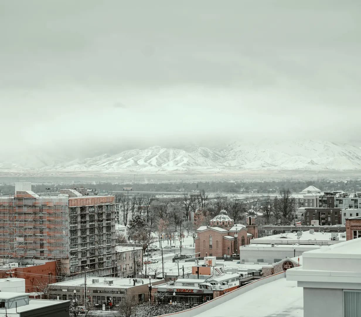 Snow-covered downtown rooftops with mountains behind on a winter day in Salt Lake City, Utah