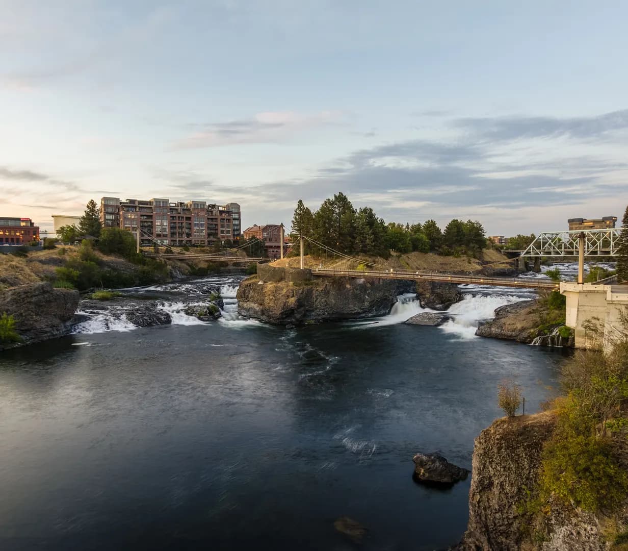 Spokane Falls and a footbridge over the Spokane River in Riverfront Park in downtown Spokane, Washington, at dusk