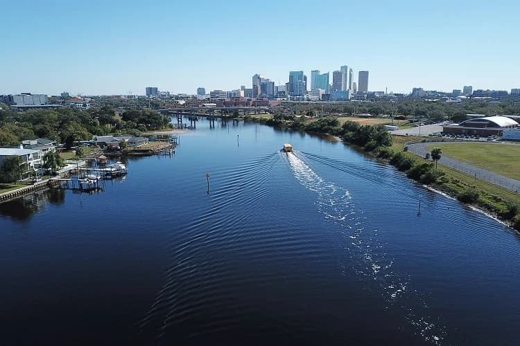 Aerial view of a boat on the waterway below the downtown Tampa, Florida skyline, a common pickup area for charter bus groups