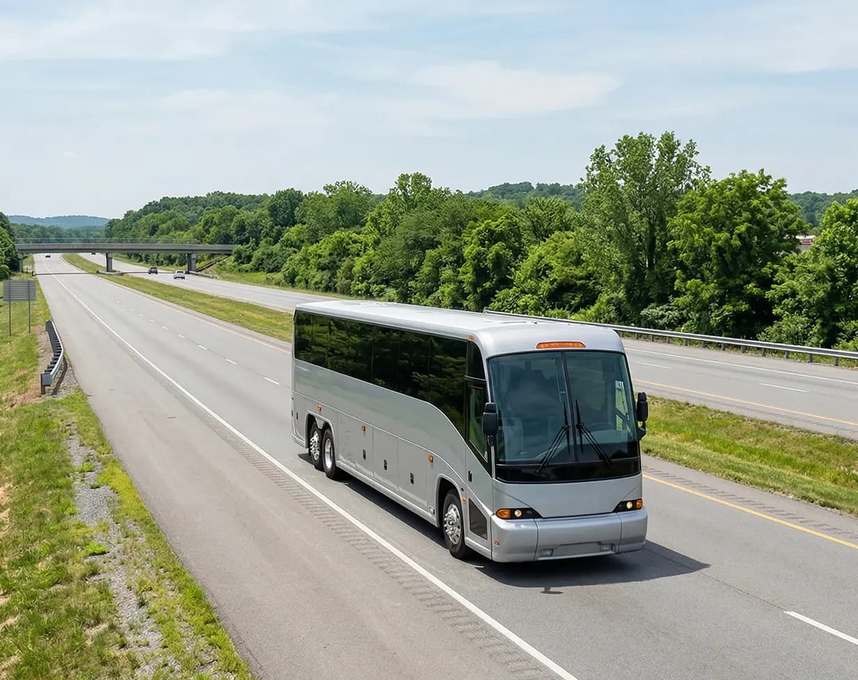 55 passenger silver charter bus rental on highway.
