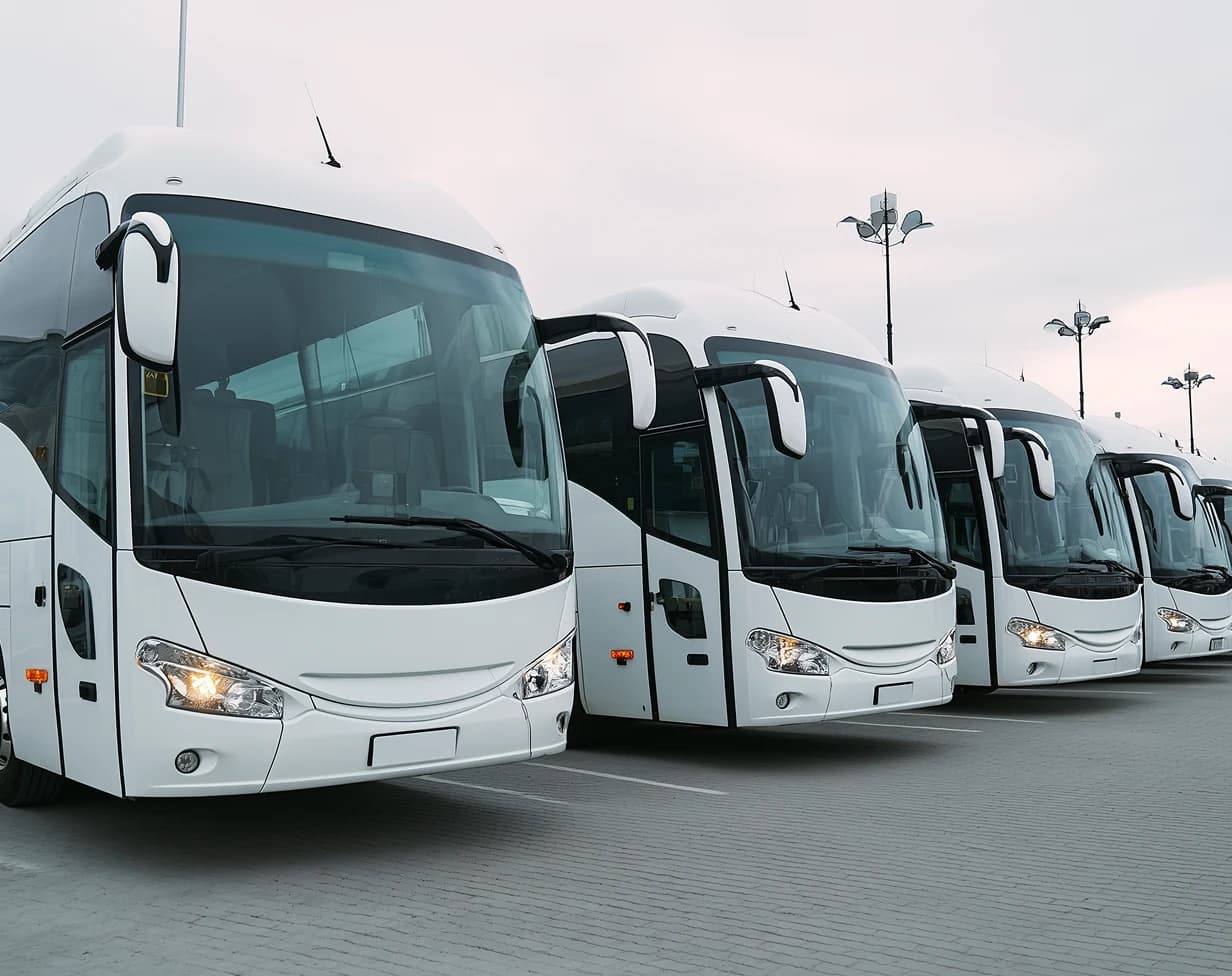 Charter bus fleet rental with white coach buses at depot.
