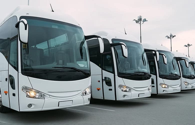 Charter bus fleet rental with white coach buses at depot.