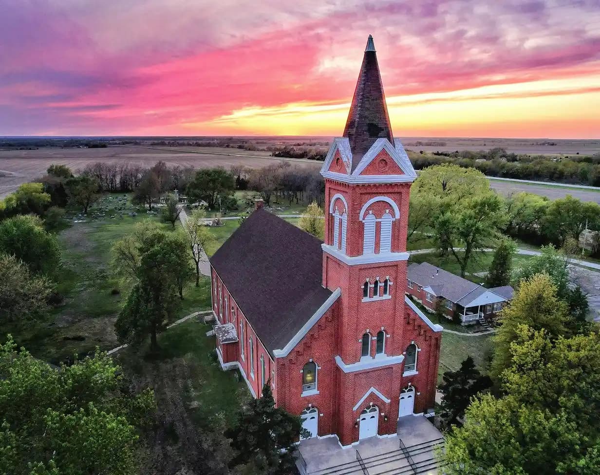 Church group charter bus transportation at red brick church sunset.