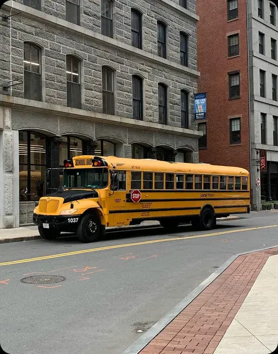 Tilted yellow school bus on city street.