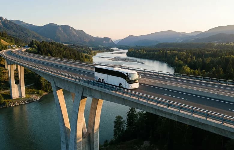 White charter bus rental on alpine bridge river aerial sunset.