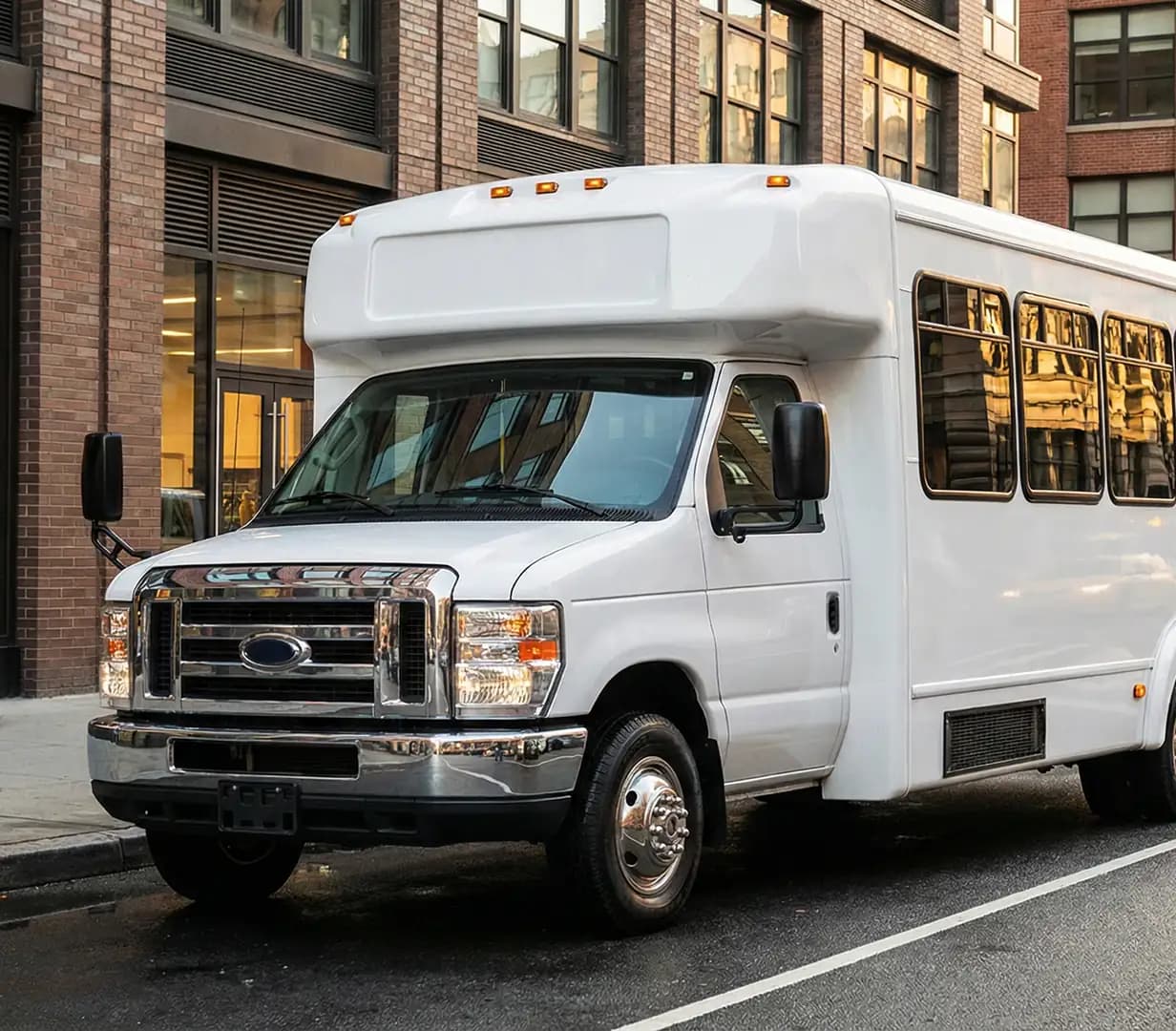 White shuttle bus parked by brick building.