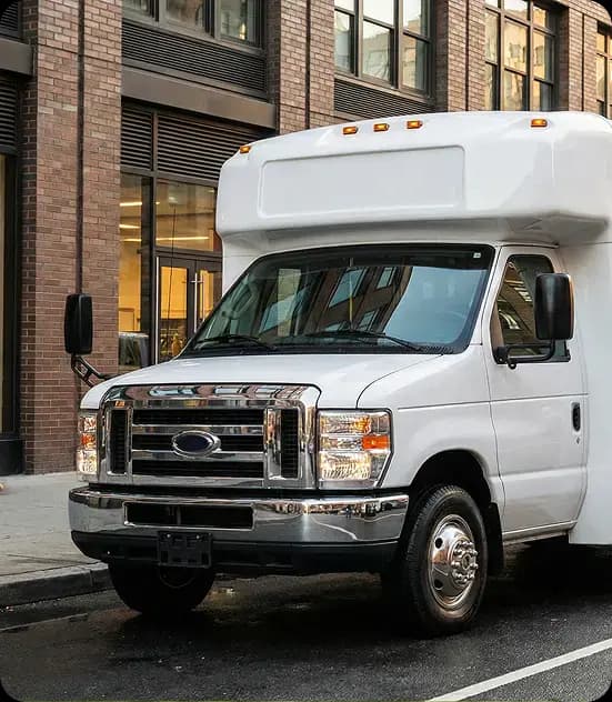 White shuttle bus parked by brick building.