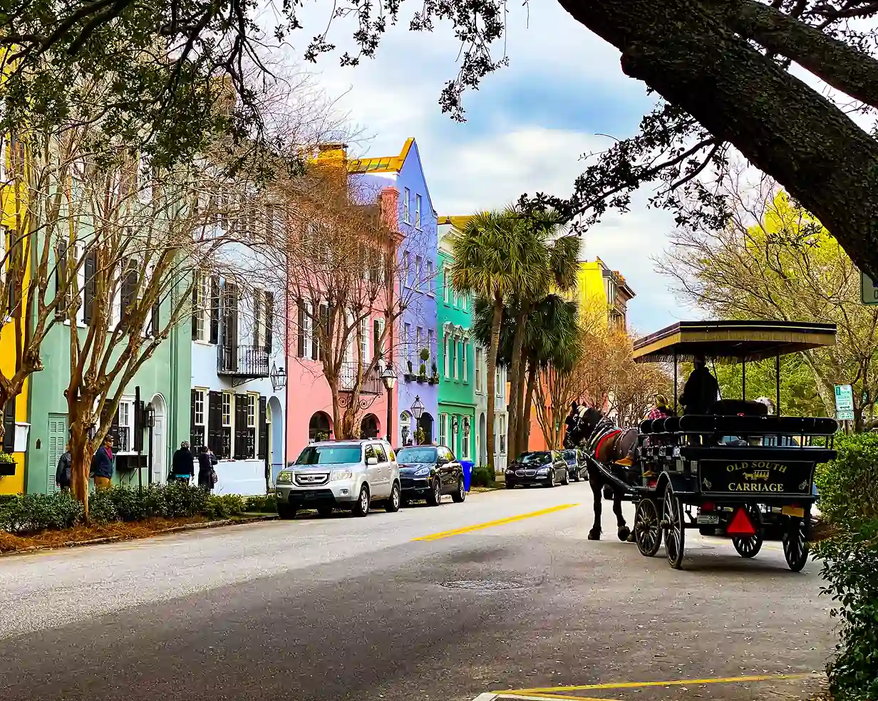 Horse-drawn carriage passing the colorful houses of Rainbow Row in downtown Charleston, South Carolina, where charter bus groups are dropped for walking tours