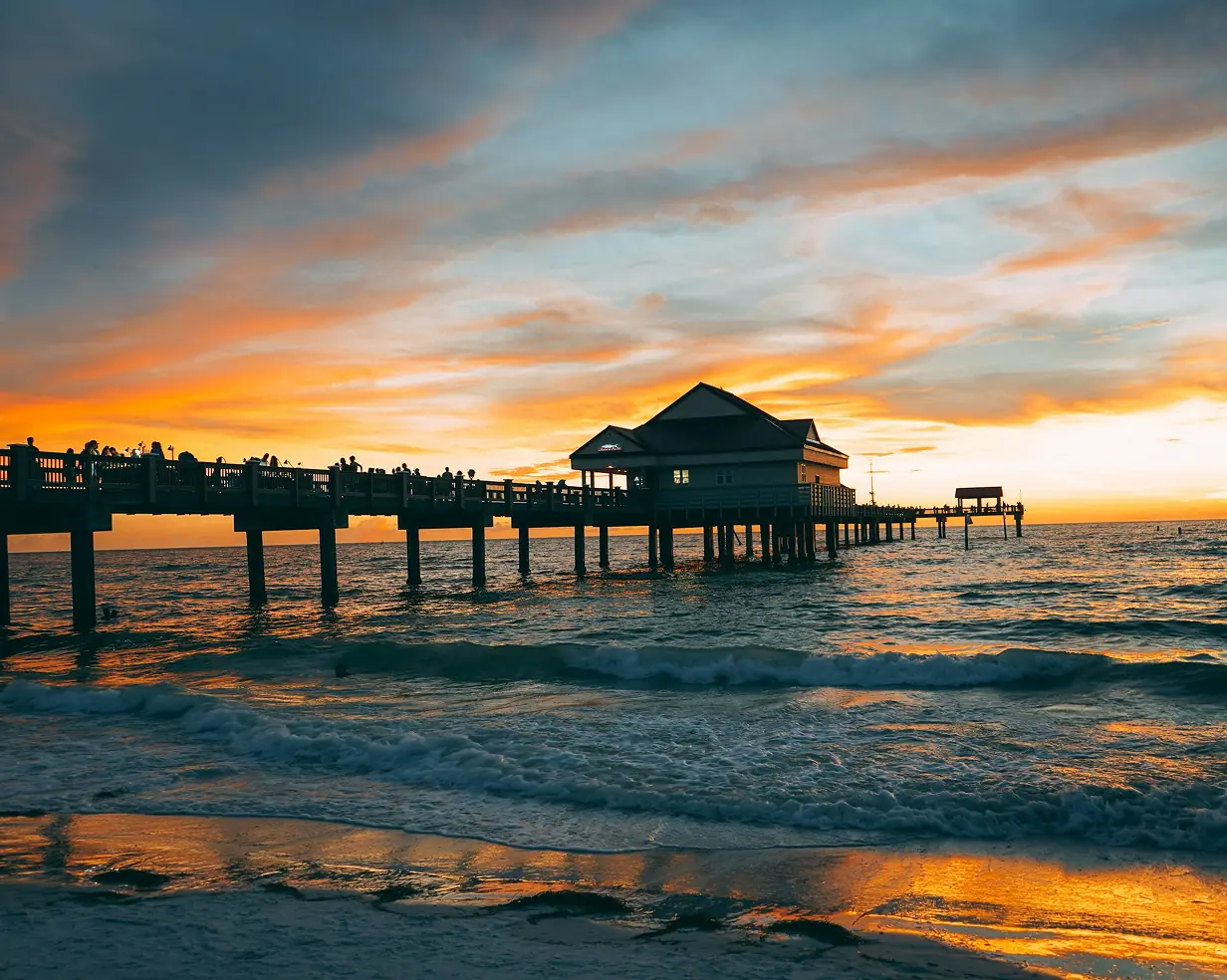 Pier silhouetted against a golden sunset over the water at Clearwater Beach, Florida, where charter bus wedding shuttles run