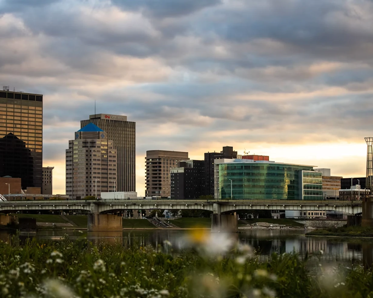 Wildflowers along the Great Miami River at sunset with the Dayton, Ohio skyline, a pickup area for charter bus groups